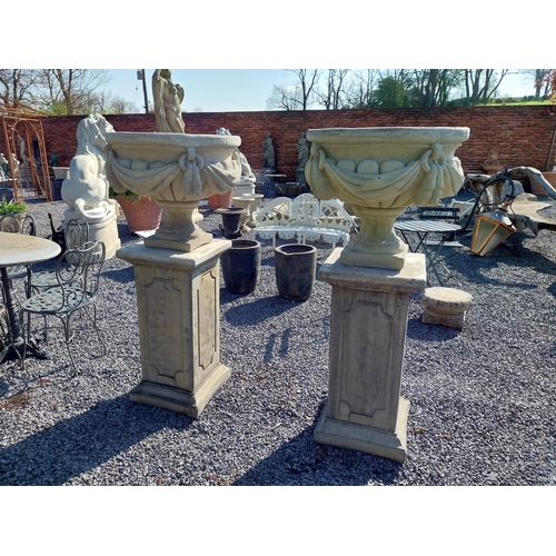 948 - Pair of moulded sandstone urns decorated with swag raised on pedestals {152 cm H x 67 cm Dia.}.