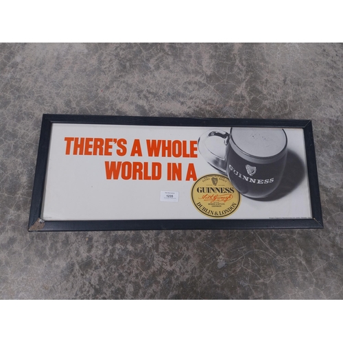 1235 - There's a Whole World in a Guinness framed showcard. {24 cm H x 49 cm W}.