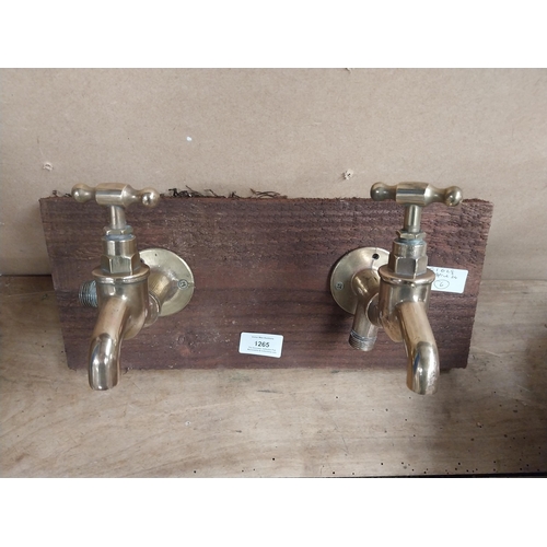 1265 - Pair of Brass taps mounted on wooden board. {14 cm H x 28 cm W}.