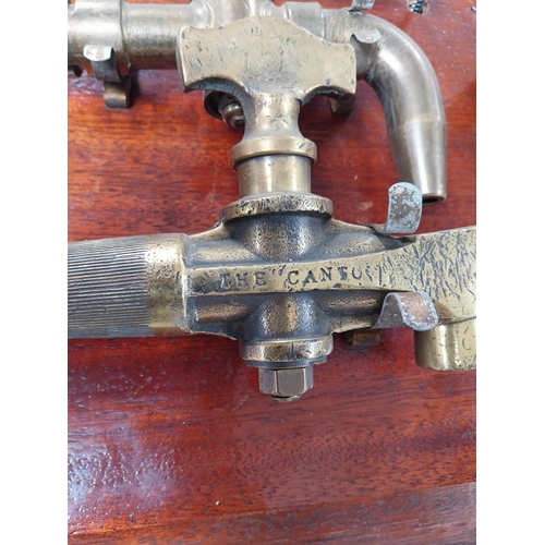 684 - Collection of nine 19th C. brass bar taps mounted on mahogany board. {32 cm H x 82 cm W}.