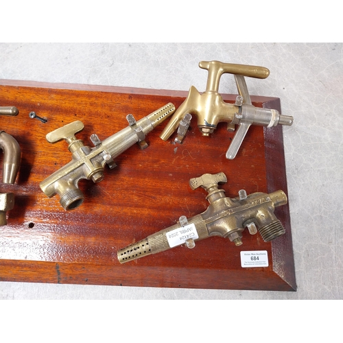 684 - Collection of nine 19th C. brass bar taps mounted on mahogany board. {32 cm H x 82 cm W}.