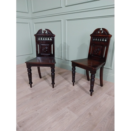 112 - Pair of Edwardian carved mahogany hall chairs raised on turned legs {88 cm H x 46 cm W x 40 cm D}.