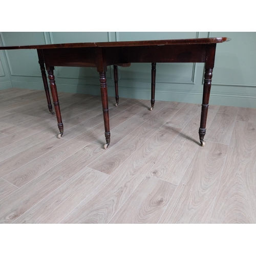 324 - Regency flamed mahogany drop leaf dining table raised on turned legs and brass and ceramic castors {... 