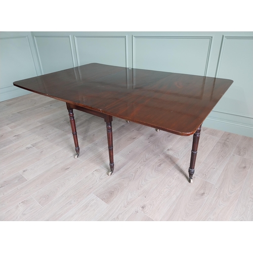 324 - Regency flamed mahogany drop leaf dining table raised on turned legs and brass and ceramic castors {... 