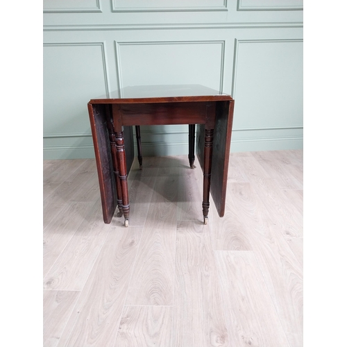 324 - Regency flamed mahogany drop leaf dining table raised on turned legs and brass and ceramic castors {... 