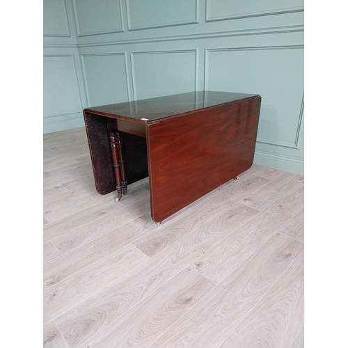 324 - Regency flamed mahogany drop leaf dining table raised on turned legs and brass and ceramic castors {... 