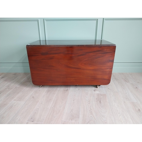 324 - Regency flamed mahogany drop leaf dining table raised on turned legs and brass and ceramic castors {... 