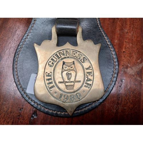 127 - Guinness Year 1980 badge and leather strap. {23 cm H x 12 cm W}