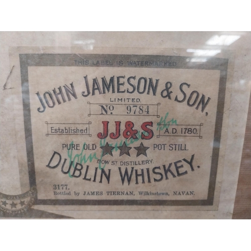 191 - Framed collection of three John Jameson and John Powers Whiskey labels. {44 cm H x 35 cm W}.