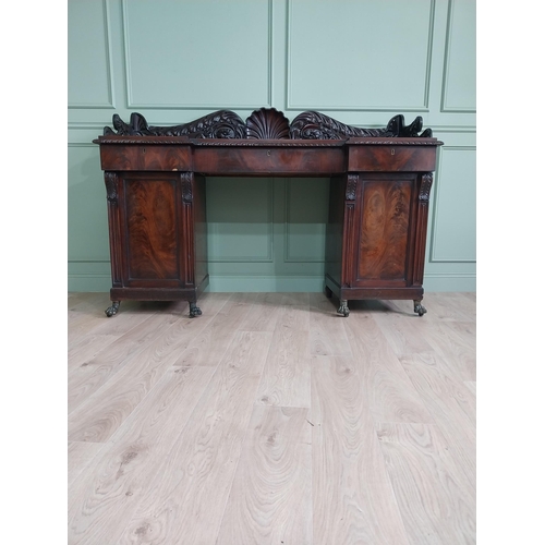 107 - Irish profusely carved mahogany sideboard with gallery decorated with central shell raised on brass ... 