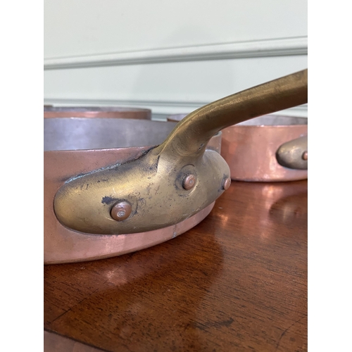 1331 - Collection of five copper saucepans with brass handles {Approx. 11 cm H x 58 cm W x 28 cm D}.