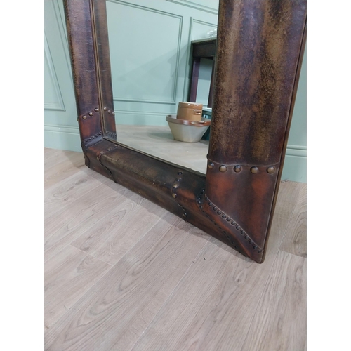 137 - Wall mirror with leather and brass studded frame {125 cm H x 96 cm W x 10 cm D}.