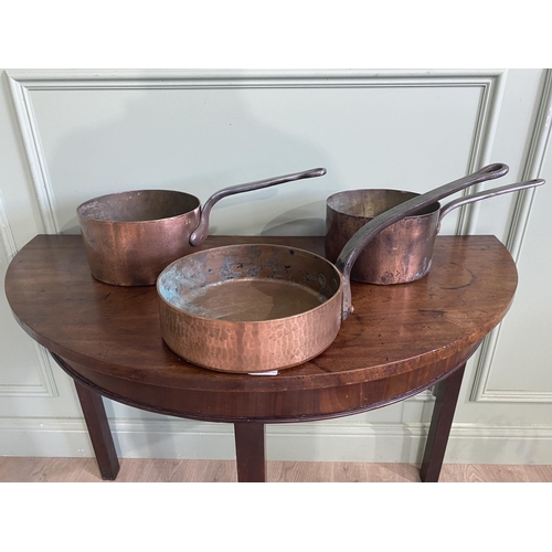 195 - Three early 20th C. heavy copper saucepans with wrought iron handles {18 cm H x 47 cm W x 22 cm D an... 