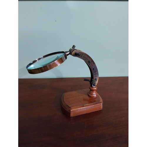 54 - Brass desk magnifying glass mounted on scumble pine base {18 cm H x 23 cm W x 10 cm D}.