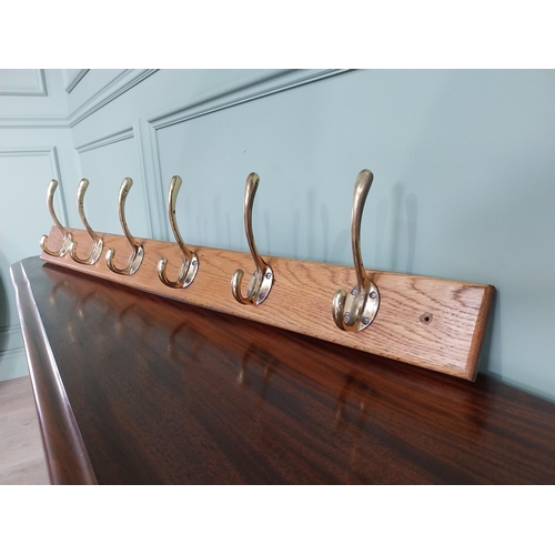 649 - Good quality set of brass coat hangers mounted on oak plaque {16 cm H x 90 cm W x 9 cm D}.