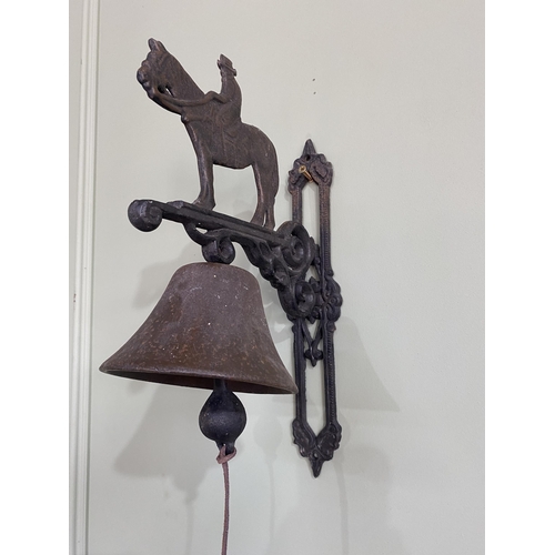 934 - Decorative cast iron wall mounted bell surmounted with horse and rider {37 cm H x 14 cm W x 25 cm D}... 