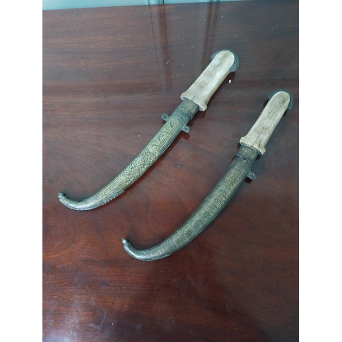 1341 - Two Middle Eastern daggers with brass engraved sheaf and horn handles {39 cm  L and 37 cm L}.