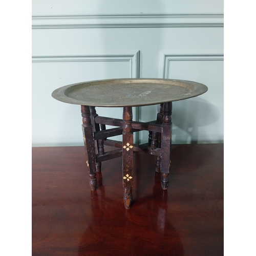 94 - Unusual early 20th C. Middle Eastern coffee table with embossed brass top and folding hardwood stand... 