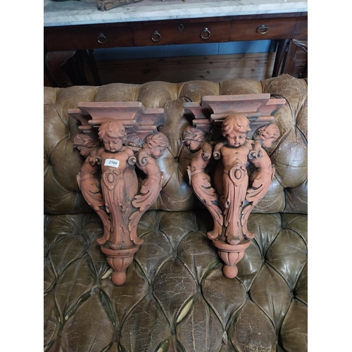 2100 - Pair of moulded terracotta wall brackets decorated with cherubs {53 cm H x 29 cm W x 19 cm D}.