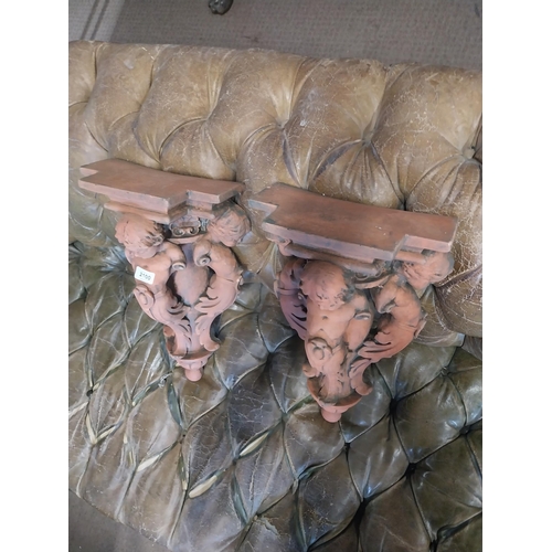 2100 - Pair of moulded terracotta wall brackets decorated with cherubs {53 cm H x 29 cm W x 19 cm D}.