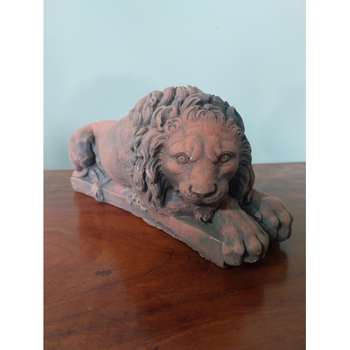 2121 - Pair of moulded terracotta statuettes of recumbent lions {13 cm H x 30 cm W x 11 cm D}.