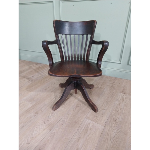 101 - 1950's oak revolving desk chair raised on four shaped outswept feet. {80 cm H x 60 cm W x 60 cm D}.