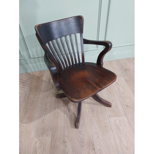 101 - 1950's oak revolving desk chair raised on four shaped outswept feet. {80 cm H x 60 cm W x 60 cm D}.