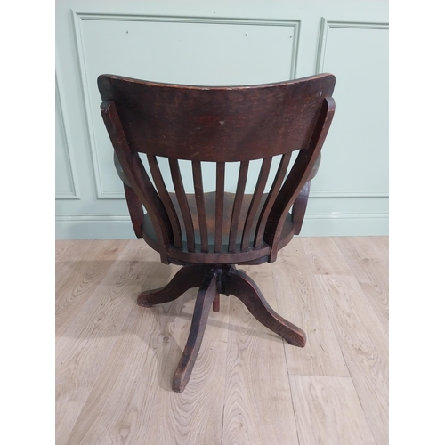 101 - 1950's oak revolving desk chair raised on four shaped outswept feet. {80 cm H x 60 cm W x 60 cm D}.