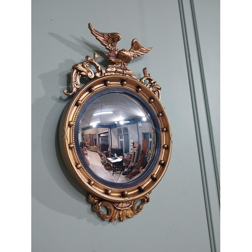 116 - Gilt convex mirror in the Victorian style surmounted by eagle. {79 cm H x 51 cm W}.