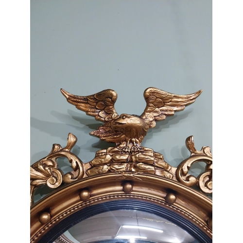 116 - Gilt convex mirror in the Victorian style surmounted by eagle. {79 cm H x 51 cm W}.