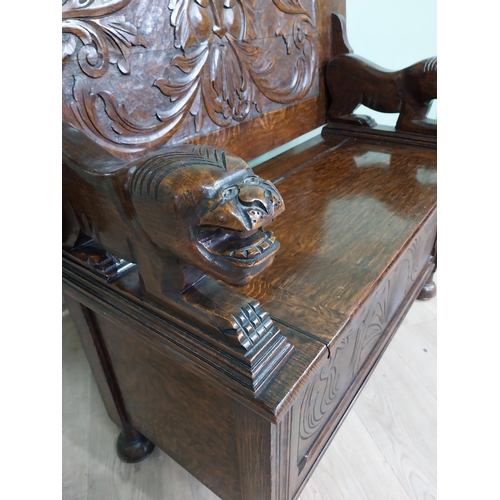 19 - Edwardian carved oak Monks bench with back depicting foliage and arms terminating in animal head rai... 