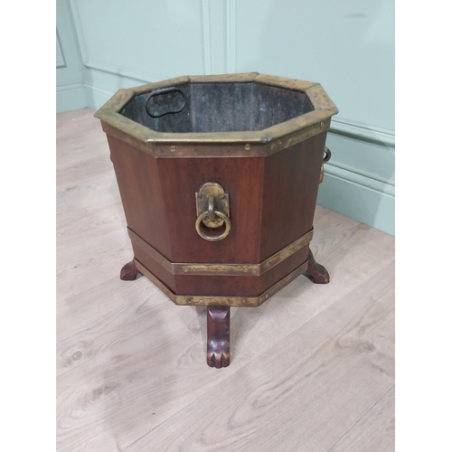 315 - Edwardian mahogany and brass octagonal log bucket with mask handles raised on four paw feet. {41 cm ... 