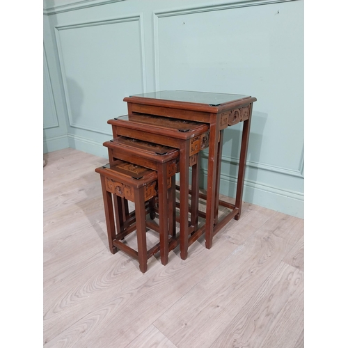 376 - Nest of four carved oriental tables with inset glass tops. {65 cm H x 51 cm W x 36 cm D}.