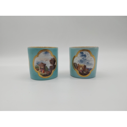 625 - Pair of 20th C. Meissen coffee can cups decorated with three gilt edged cartouches depicting rural s... 