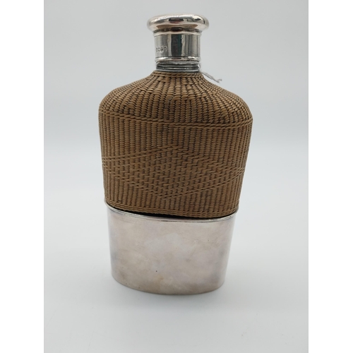 760 - Whiskey hip flask with basket weave wicker half cover and English silver mounts. Hallmarked in Londo... 