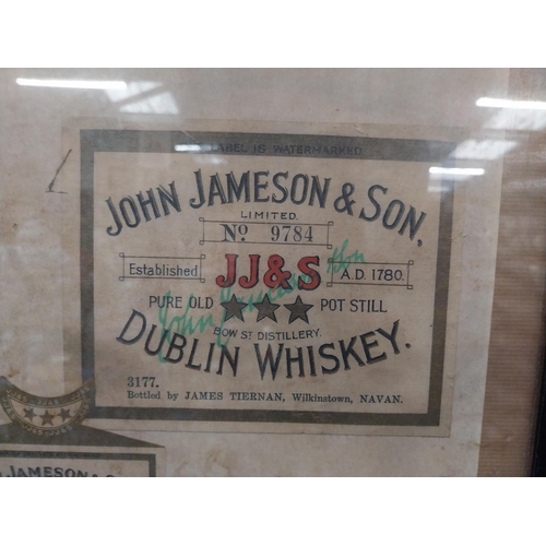 107 - Framed collection of three John Jameson and John Powers Whiskey labels. {44 cm H x 35 cm W}.