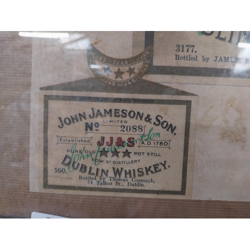 107 - Framed collection of three John Jameson and John Powers Whiskey labels. {44 cm H x 35 cm W}.