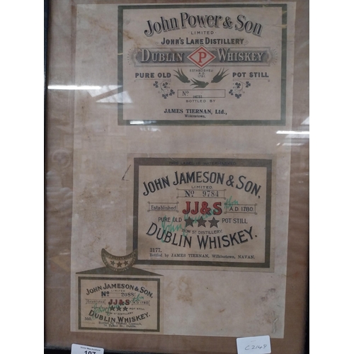 107 - Framed collection of three John Jameson and John Powers Whiskey labels. {44 cm H x 35 cm W}.