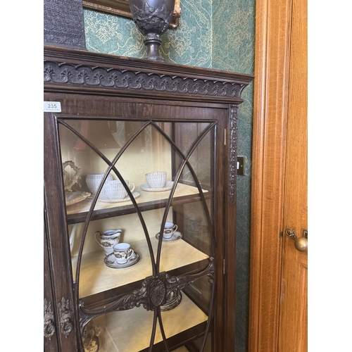 235 - Edwardian carved oak display cabinet with two astragal glazed doors, raised on square tapered legs. ... 