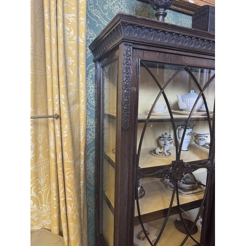 235 - Edwardian carved oak display cabinet with two astragal glazed doors, raised on square tapered legs. ... 