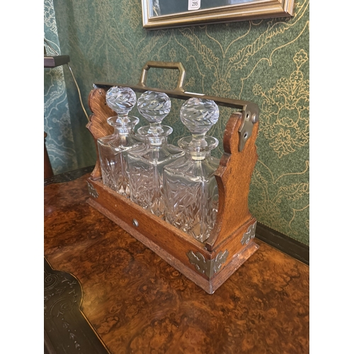 296 - Edwardian oak tantalus with brass mounts and three cut glass decanters. {35 cm H x 42 cm W x 16 cm D... 