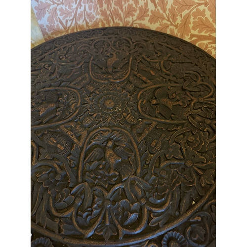 723 - Oriental oak occasional table, the circular top carved with HoHo birds, raised on three spiral legs.... 