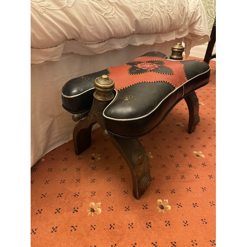 867 - Camel stool with tooled leather top, brass knobs and shaped supports. { 40cm H X 63cm W X 33cm D }.