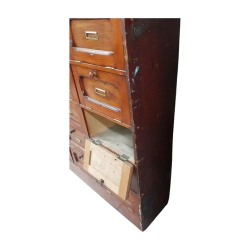 40 - Early 20th C. stained pine office cabinet with twenty one drop down doors with brass mounts. {171 cm... 