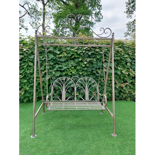 616 - Decorative bronzed painted wrought iron garden swing. {217 cm H x 147 cm W x 96 cm D}.