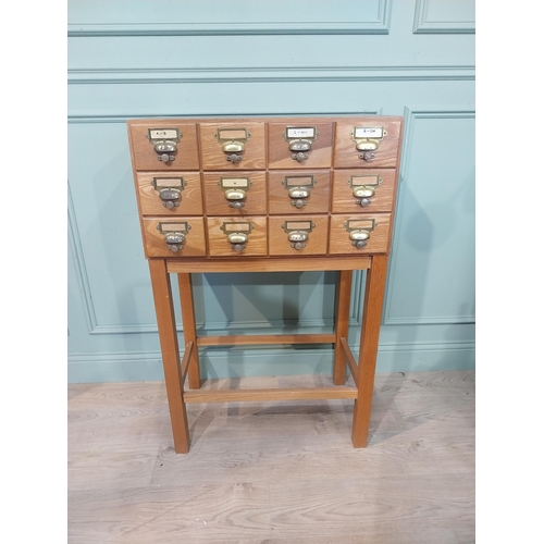 46 - 1950's oak bank of twelve drawers with brass handles on square legs. {104 cm H x 68 cm W x 41 cm D}.