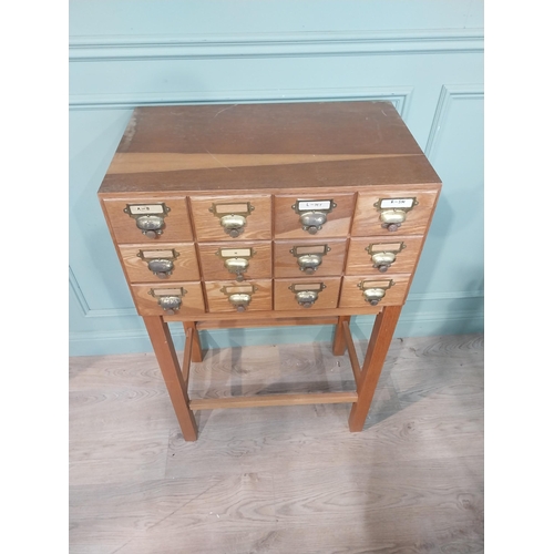 46 - 1950's oak bank of twelve drawers with brass handles on square legs. {104 cm H x 68 cm W x 41 cm D}.