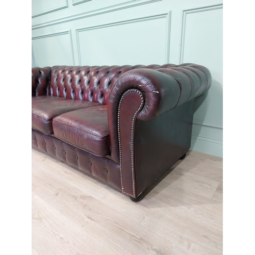 13 - Oxblood leather deep buttoned three seater Chesterfield sofa. {70 cm H x 200 cm W x 82 cm D}.