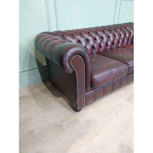 13 - Oxblood leather deep buttoned three seater Chesterfield sofa. {70 cm H x 200 cm W x 82 cm D}.