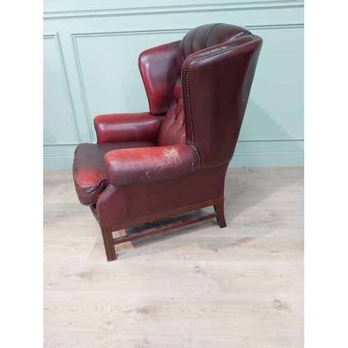 15 - Oxblood leather deep buttoned Chesterfield wingback armchair. {106 cm H x 90 cm W x 90 cm D}.